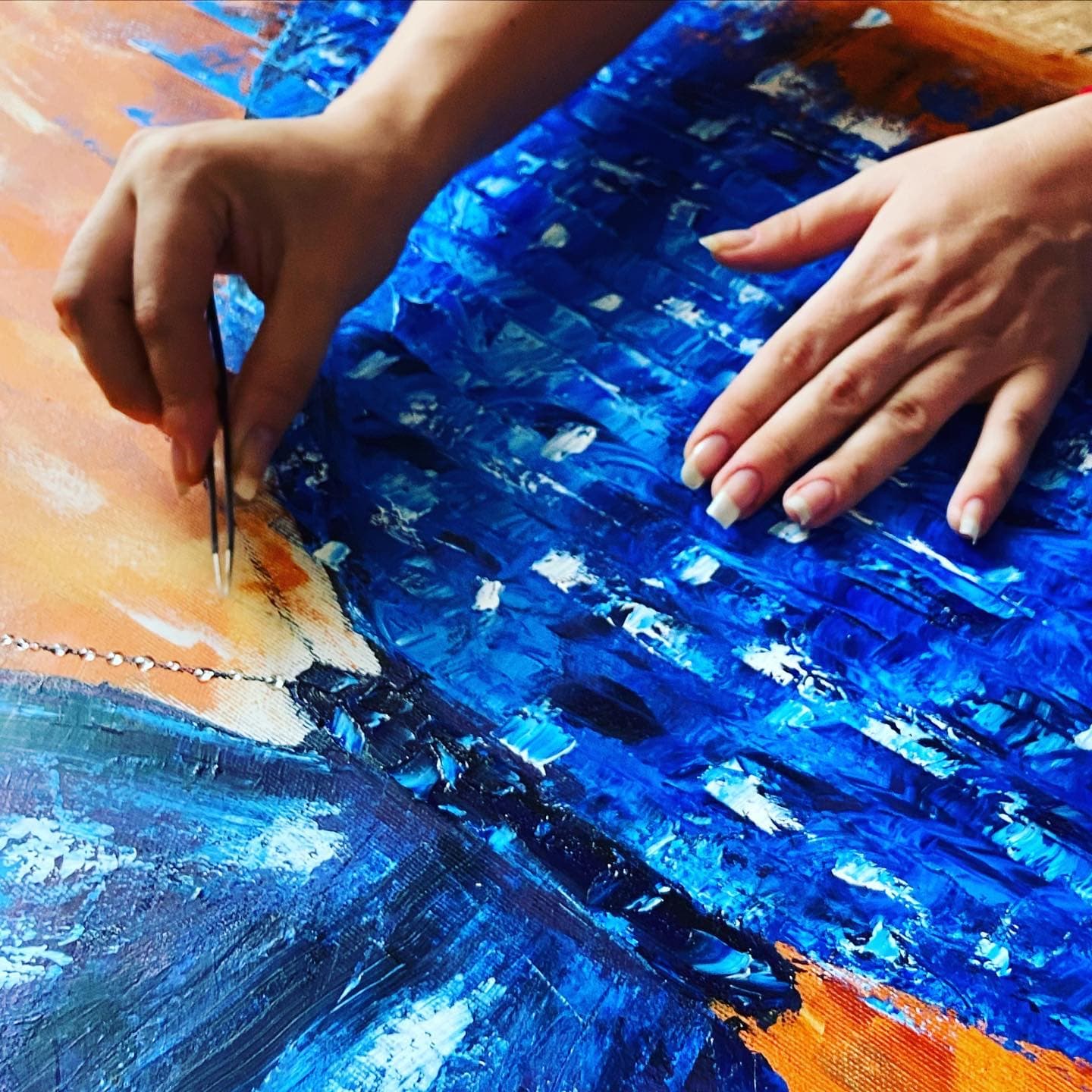 Helen She's hands on the canvas: with tweezers she places a line of tiny clear drops along the edge of the blue wing.